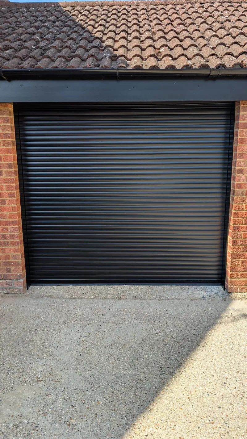 After: new black insulated roller garage door fitted by Rollrite to the same brick garage
