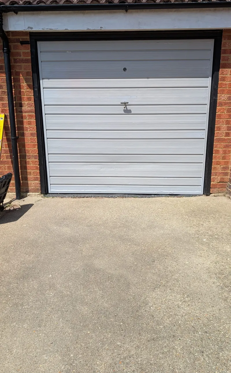 Before: worn silver up-and-over garage door on a brick garage ahead of a Rollrite upgrade